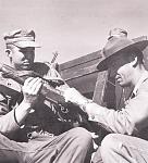 Preparing to fire the M-1 rifle for qualifications. DI Sgt Kling instructs a member of the platoon on safety and loading OF the magazine. Up to the...